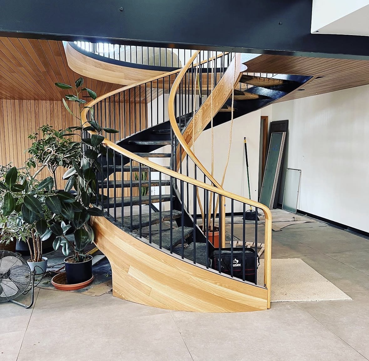 Curved staircase with wood handrails and black metal balusters