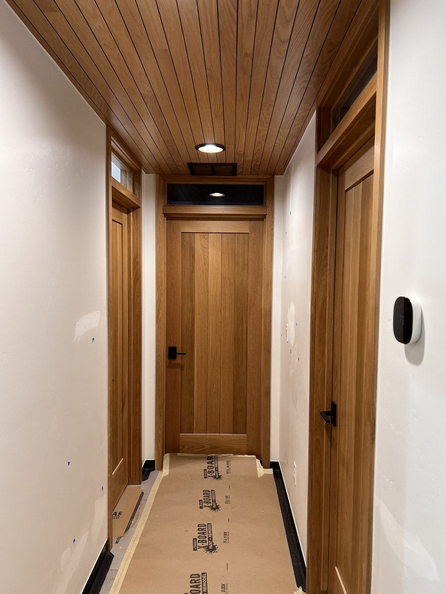 Interior wood panel doors with transom windows and a wood ceiling in a hallway