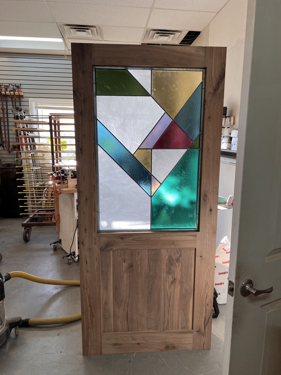 Wood door with geometric stained glass, pictured in the workshop
